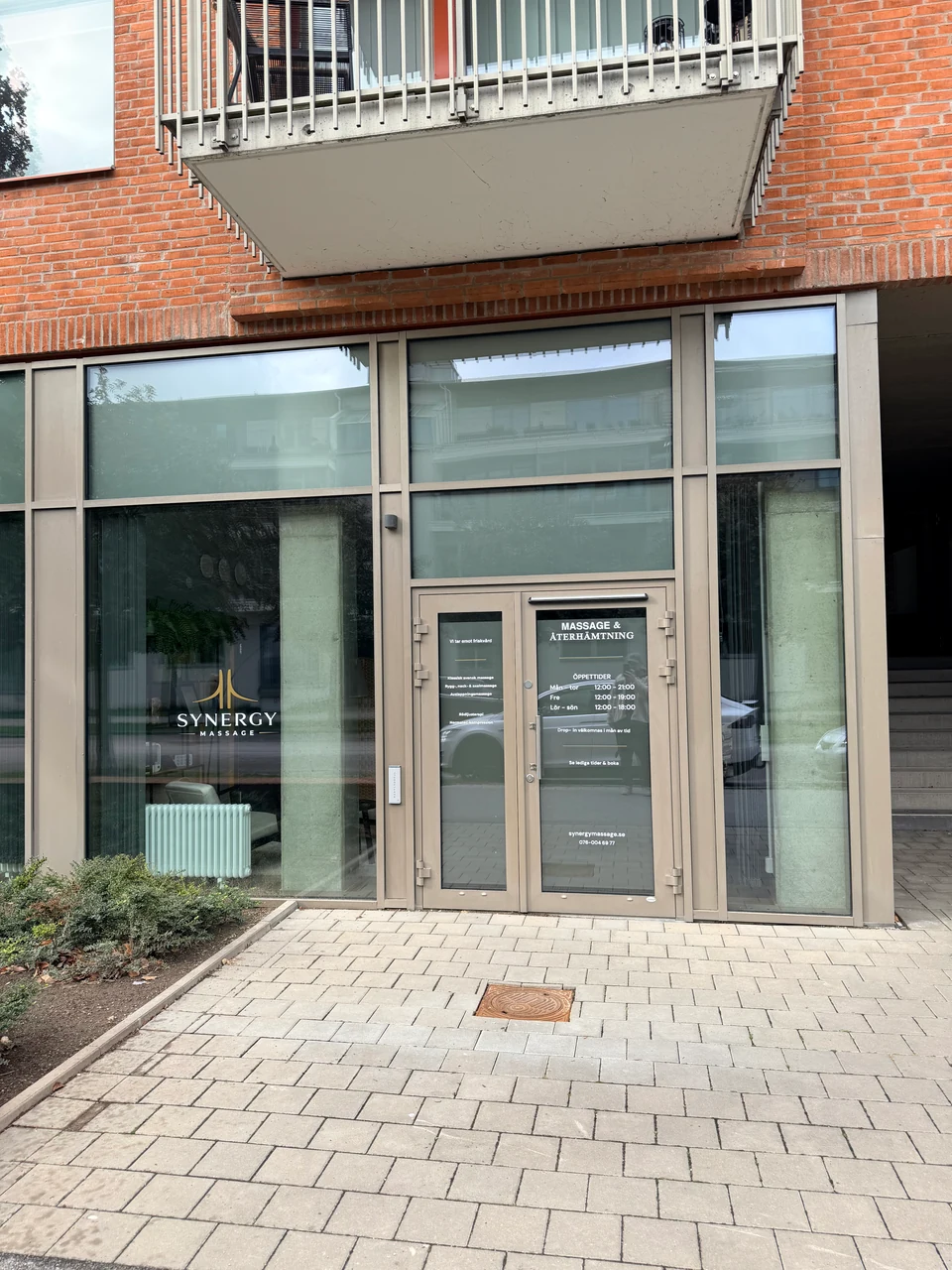 Synergy Massage från gatan på Sundholmsgatan 10, med logotypen i skyltfönstret och ingången till höger.